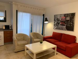 プラヤ・ブランカにあるLa Botavara Apartmentのリビングルーム(赤いソファ、椅子2脚、テーブル付)