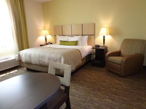 a hotel room with a large bed and a chair at Candlewood Suites Odessa, an IHG Hotel in Odessa