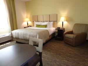 a hotel room with a large bed and a chair at Candlewood Suites Odessa by IHG in Odessa