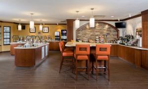 ein Restaurant mit einer Bar mit orangefarbenen Barhockern in der Unterkunft Staybridge Suites Montgomeryville, an IHG Hotel in North Wales