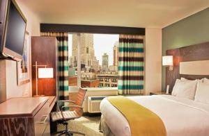 a hotel room with a bed and a large window at Holiday Inn Express - Times Square South, an IHG Hotel in New York