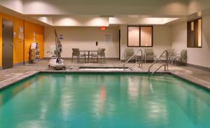 a swimming pool in a room with a table and chairs at Holiday Inn Express & Suites Overland Park, an IHG Hotel in Overland Park