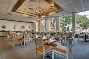 a dining room with tables and chairs and windows at Holiday Inn Westbury-Long Island by IHG in Carle Place