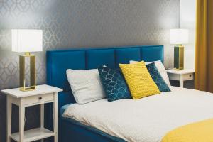 een slaapkamer met een blauw bed en 2 nachtkastjes bij FatCat Apartments in Krakau
