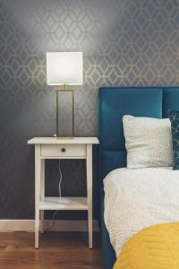 a bedroom with a bed and a table with a lamp at FatCat Apartments in Krakow