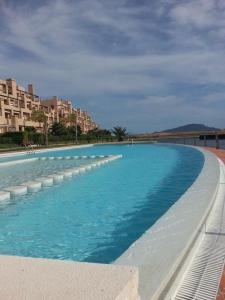 uma grande piscina com água azul e edifícios em Sol y descanso em Alhama de Múrcia