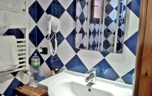 a bathroom with blue and white tiled walls and a sink at Arcamyrtus in Alghero