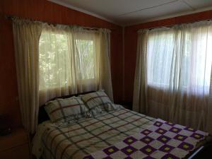 Un dormitorio con una cama y dos ventanas en Cabana Caburgua, en Caburgua