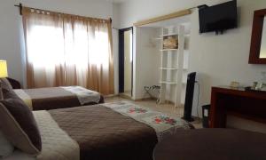 a hotel room with two beds and a flat screen tv at Hotel San Miguel Penjamo in Pénjamo