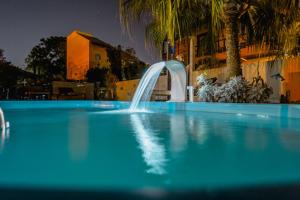 uma piscina com uma fonte de água em frente a um edifício em Pousada Santa Genoveva campeche em Florianópolis