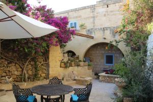 an outdoor patio with a table and chairs and flowers at The Garden Gate in Sannat