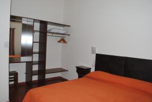 1 dormitorio con 1 cama con colcha de color naranja en Ayuntunhue Apart Hotel en San Bernardo
