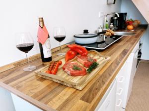 ein Schneidebrett mit Fleisch und Gemüse sowie eine Flasche Wein in der Unterkunft Apartments Fichtelberger Blick in Kurort Oberwiesenthal