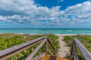a boardwalk to the beach with a view of the ocean at Chateau de la Mer in Jensen Beach