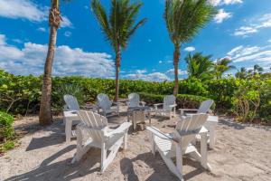 a group of chairs and palm trees on the beach at Chateau de la Mer in Jensen Beach