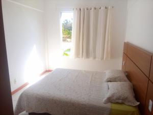 um quarto com uma cama e uma janela em Apto. Vila dos Lírios - Reserva Imbassai em Imbassaí