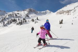 a woman and a child on skis in the snow at The Lodge at Snowbird in Alta