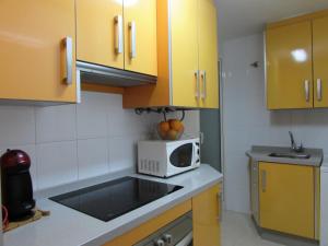 una cucina con armadi gialli e forno a microonde di Garrucha Apartment a Garrucha