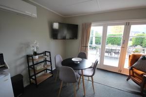 ハンマー・スプリングスにある3 Woodbank Roadのテーブルと椅子、バルコニーのあるリビングルーム