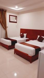 two beds in a hotel room with two bedsskirts at Iwan Alandalusia Al Ajaweed in Jeddah