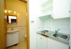 a white kitchen with a sink and a toilet at Apartments and rooms Ljuba - 130 meter from sea in Makarska