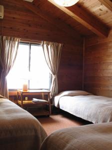 a bedroom with two beds and a window at Pension Sanrinsha in Shizukuishi