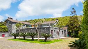 ein Steinhaus mit Bäumen davor in der Unterkunft Quinta do Torcaz in Horta