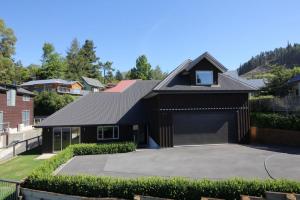 una casa nera con un garage in un cortile di 38 St James Avenue a Hanmer Springs