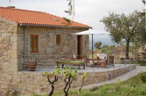 a stone house with a table and an umbrella at Casa da Carriça - Serra da Estrela in Guarda