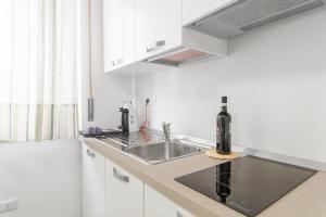 Una cocina con fregadero y gabinetes blancos. en Acquaviva Apartments, en Nápoles