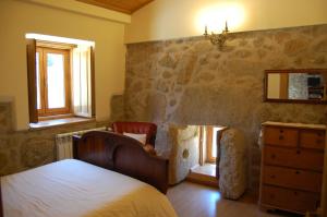 een slaapkamer met een bed, een dressoir en ramen bij Casa da Carriça - Serra da Estrela in Guarda