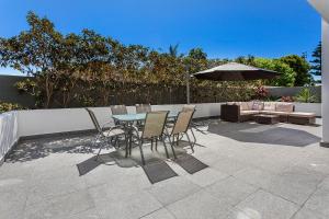 a patio with a table and chairs and an umbrella at Kiama Seaside Getaway in Kiama