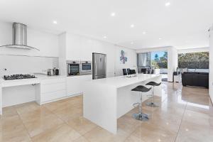 a white kitchen with a counter and a stove at Kiama Seaside Getaway in Kiama