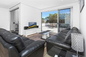 a living room with a leather couch and a tv at Kiama Seaside Getaway in Kiama