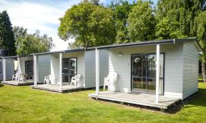 a white house with white chairs on a yard at Marahau Beach Camp in Marahau