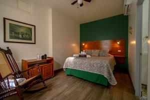 - une chambre avec un lit et un mur vert dans l'établissement Alice y Juancito Boutique Hotel, à Alajuela