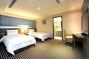 um quarto de hotel com duas camas e uma secretária em International Citizen Hotel em Kaohsiung
