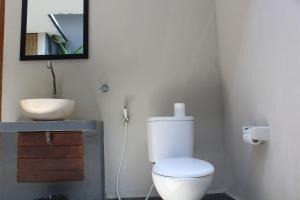 a bathroom with a white toilet and a sink at Singabu Bungalows in Nusa Penida