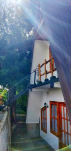 a white building with red windows and a view at La Luna Cabins in Nuwara Eliya