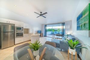 a kitchen and living room with a couch and a table at Saltwater Luxury Apartments in Port Douglas