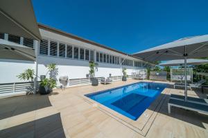 a house with a swimming pool and an umbrella at Saltwater Luxury Apartments in Port Douglas