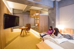 2 filles assises sur un lit dans une chambre d'hôtel dans l'établissement Sakura Cross Hotel Tokyo Kayabacho, à Tokyo