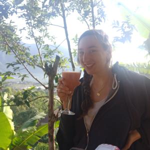 a woman holding a drink in her hand at ECO Bedugul adventurer camp in Bedugul
