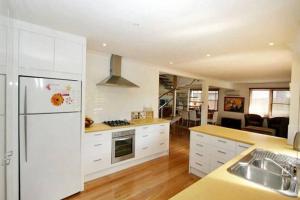 a kitchen with white cabinets and a white refrigerator at Illalangi - views, pool, walk to beach in North Haven