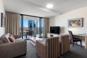 iStay River City Brisbane في بريزبين: غرفة معيشة مع أريكة ومكتب وتلفزيون