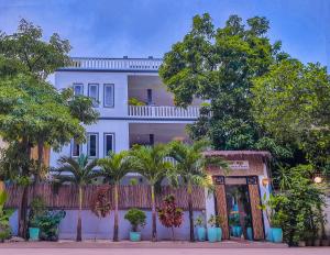 a white building with palm trees in front of it at Plumeria Hotel & Spa in Siem Reap