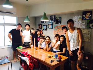 a group of people standing around a table in a room at Loft18 Hostel in Tainan