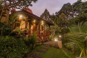 Be Bali Hut Farm Stay في أوبود: منزل به أضواء في حديقة في الليل