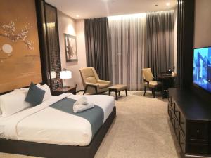 a hotel room with a bed and a flat screen tv at Vangohh Eminent Hotel & Spa in Bukit Mertajam