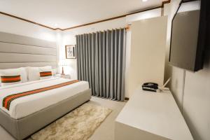 a hotel room with a bed and a television at Sur Beach Resort Boracay in Boracay